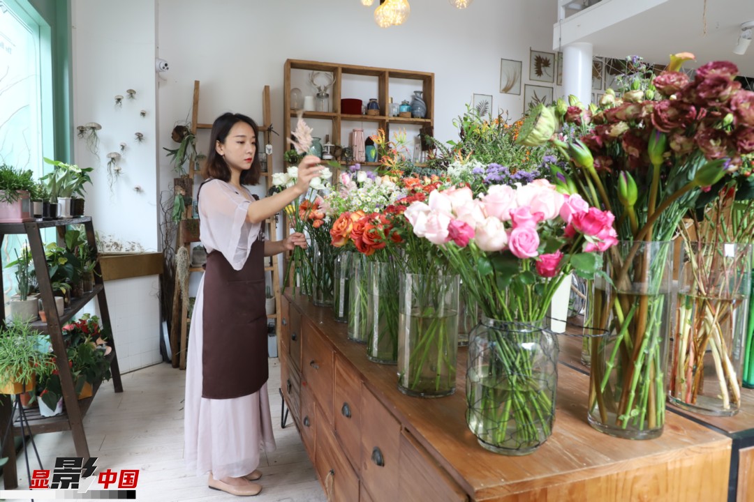王黎媛是一名河南姑娘，在昆明念完大學(xué)后，就再也舍不下春城的藍(lán)天陽光、青山碧水，更舍不下這里的四時繁花，于是就干脆留了下來，成了一名媒體人。2017年的時候又毅然辭去工作，創(chuàng)業(yè)開起了花店，成了都市里的一名“花房姑娘”。圖為王黎媛在自己的花店中整理鮮花。新華網(wǎng) 周亞平/攝 念新洪/文